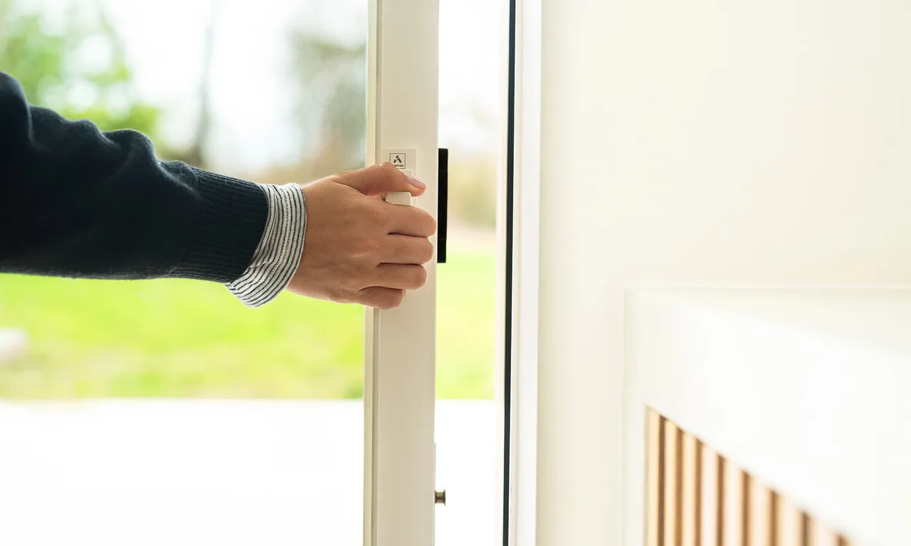 A hand sliding open a minimalist glass door